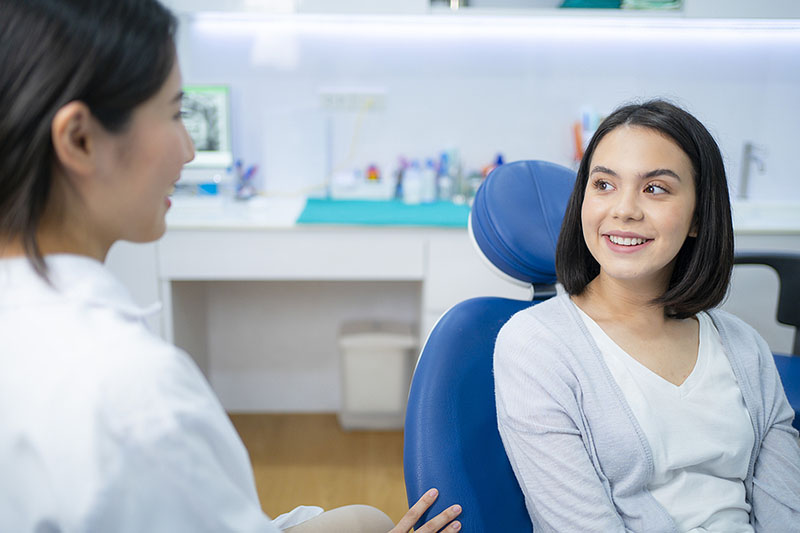 Dentist consults young patient sitting in dental chair