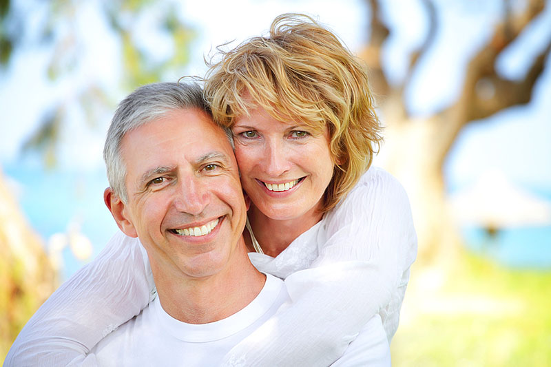 Older couple smiling with dental crowns