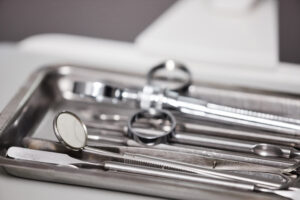 Sterile dental tools sit on a metal tray