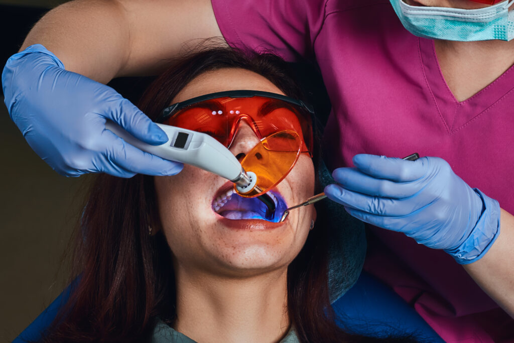 Dentist treats a patient using laser dentistry device