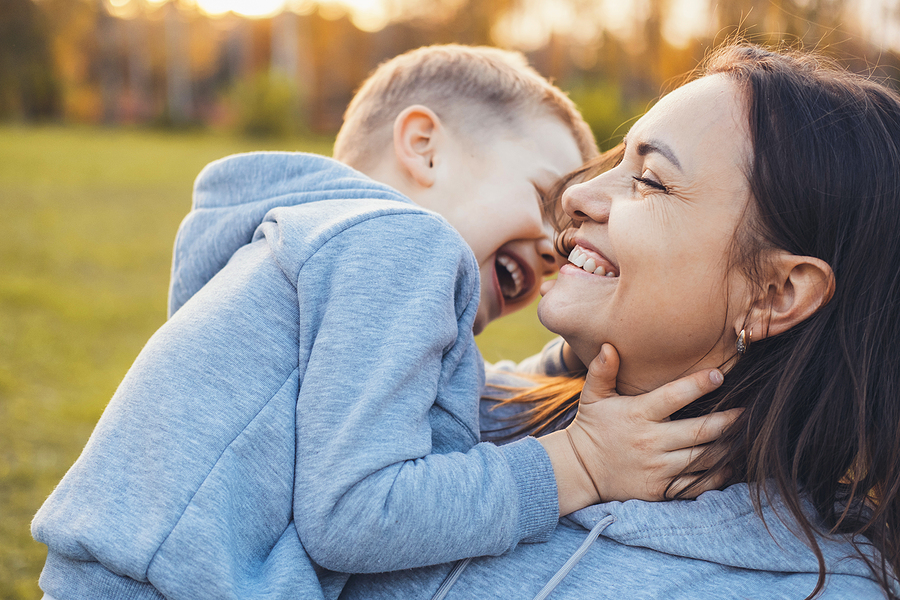 Mother and Son A mother walking through the autumn park carrying her laughing son