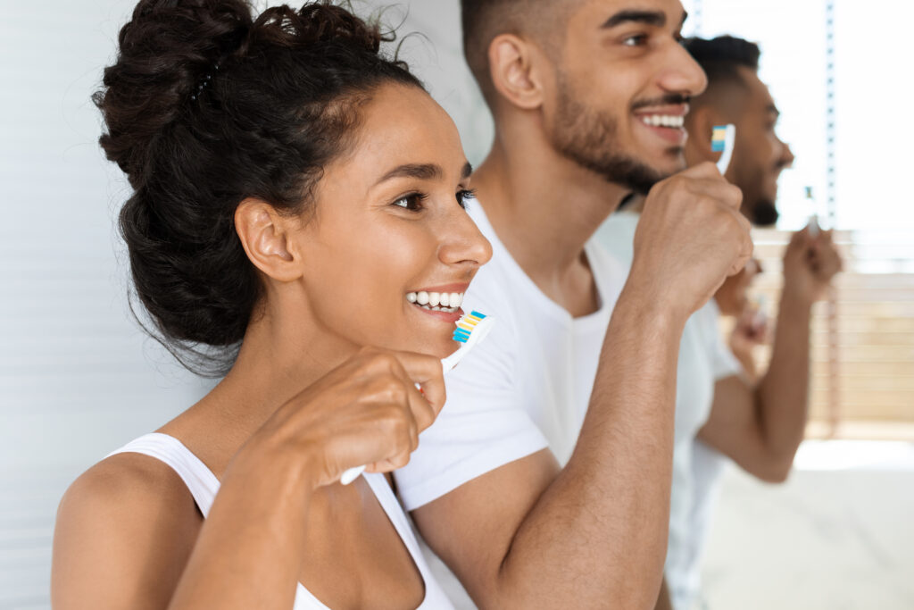 Closeup Shot Of Young Couple Brushing Teeth Together Young couple smiles and brushes their teeth.