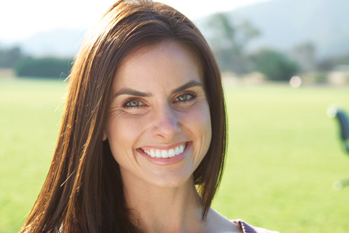Woman with bright white teeth smiling outside